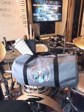 Load image into Gallery viewer, Symmetrical Drumming V3 - Duffel Bag (Grey) - Large kit bag sitting on drums holding drumsticks and sheet music - side view - Keen Eye Design